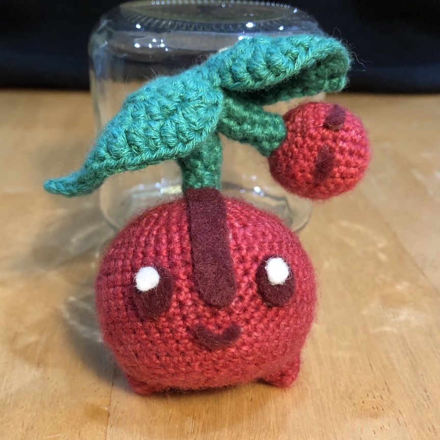 crocheted cherubi facing straight ahead, propped up by a glass jar