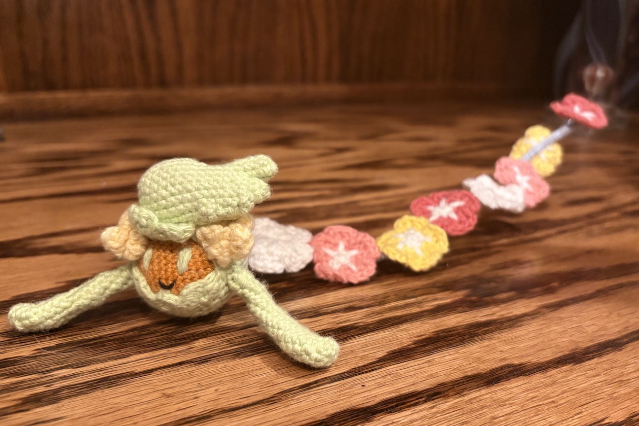 Crocheted comfey with her flowers stretched behind her rather than in a circle