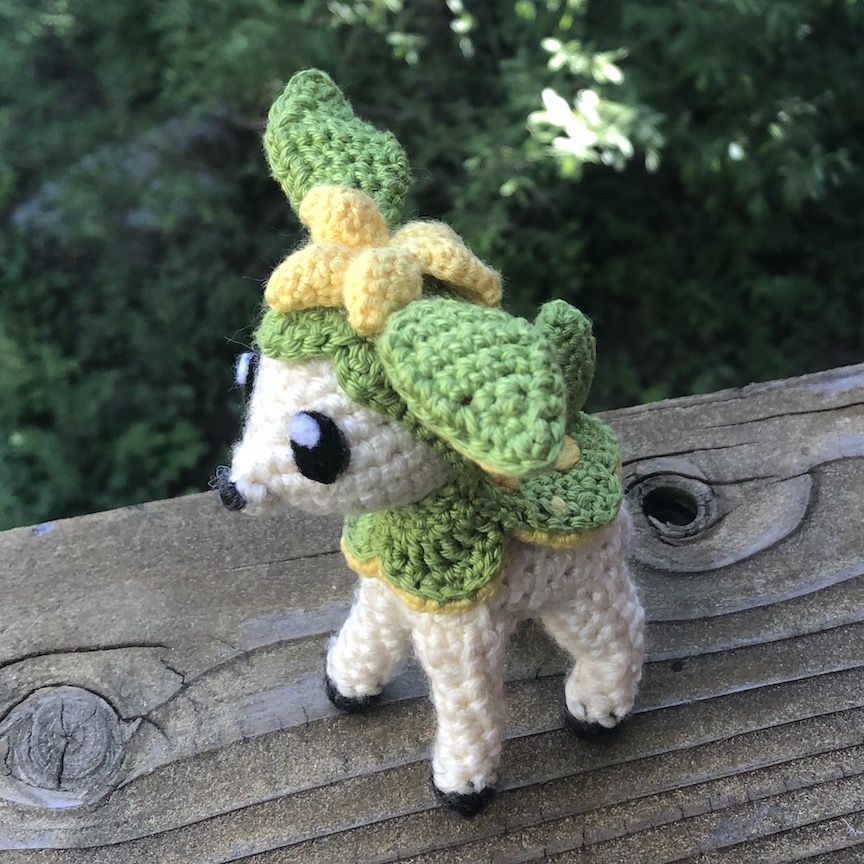 Crocheted deerling in her green summer coat, facing towards the left