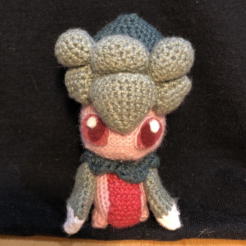 Crochet fomantis standing and looking right at the camera.