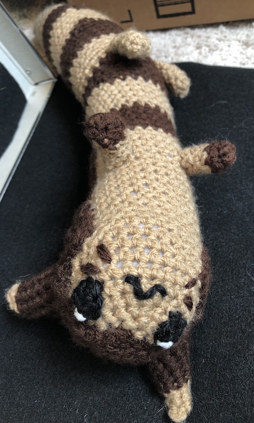 crocheted furret on its back, legs in the air