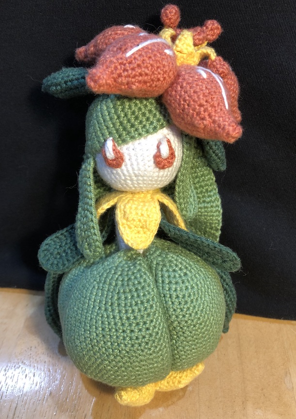 Crocheted lilligant out of her pot indoors, with her little yellow petal feet