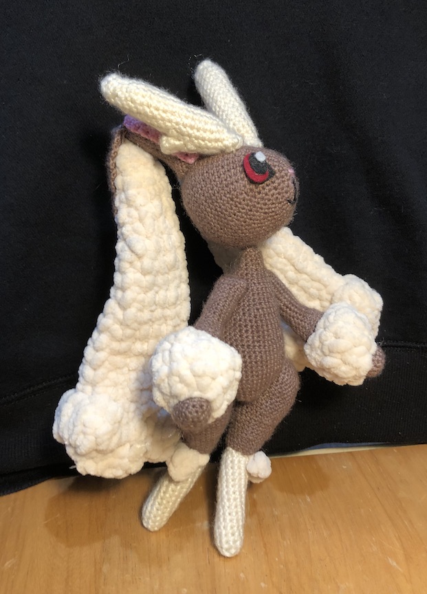 crocheted lopunny looking up and to the side, one leg slightly lifted like she's delivering a dramatic line in a play