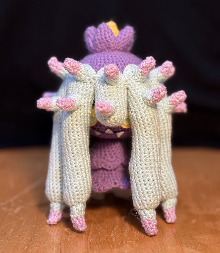 Crochet mareanie facing you with all of her tentacles pressed in tightly, as small as possible