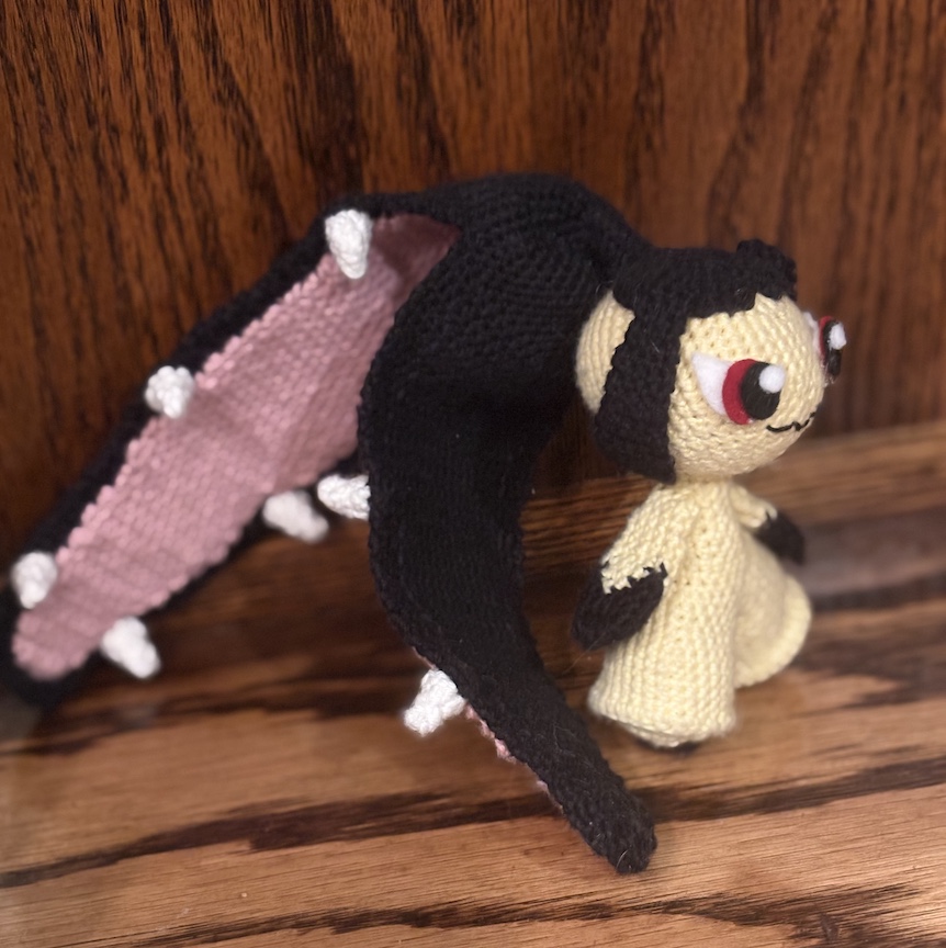 crocheted mawile at an angle with her ponytail mouth slightly open to show off her teeth