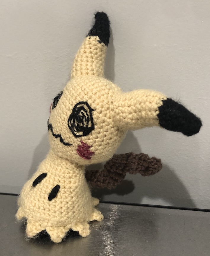 A different crocheted mimikyu, this one with the more standard pale yellow. It looks off at an angle