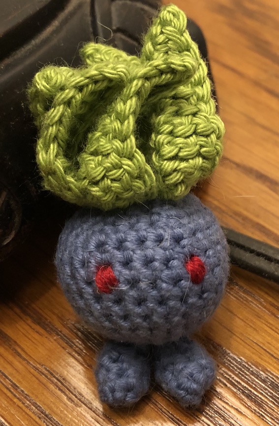 Smaller crocheted oddish with yarn sewn eyes looking straight ahead