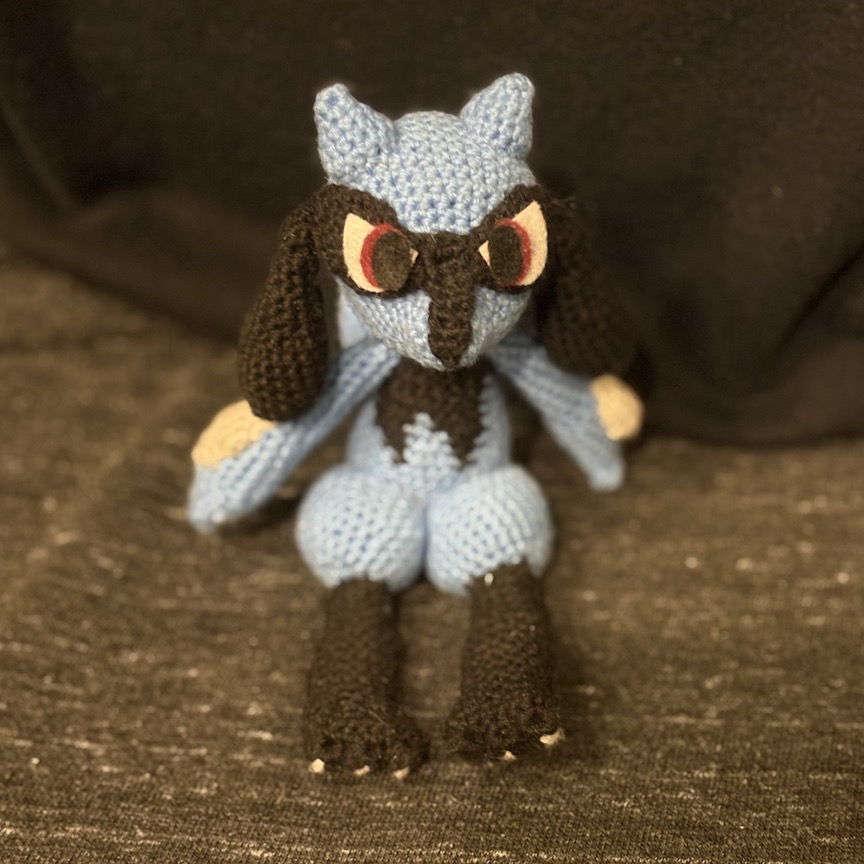 Crocheted riolu sitting facing you