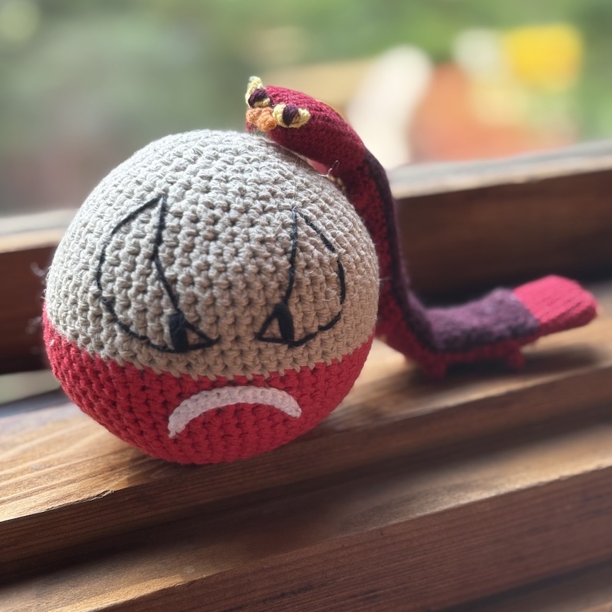 Crocheted sizzlipede arched over crocheted Hisuian electrode in a little hug