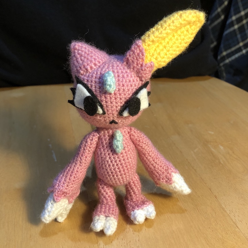 shiny crocheted sneasel facing you with large stylized felt eyes and a mouth like an upside down v