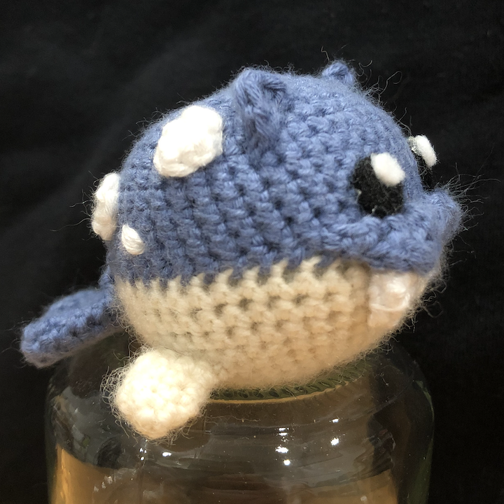 crocheted spheal from the side, perched on a glass jar