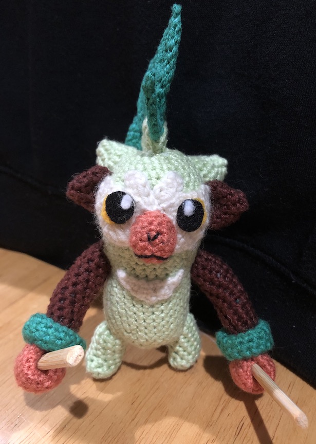 Crocheted thwackey with a cute little face staring at you, his sticks at rest