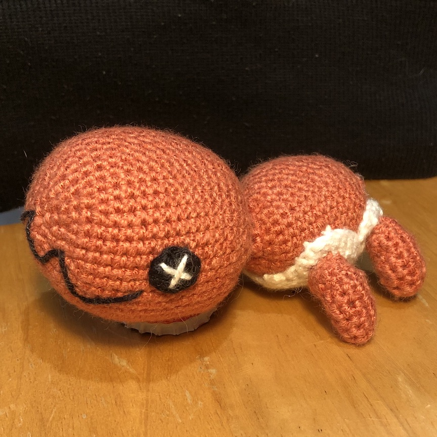 crocheted trapinch facing left and head resting on the ground