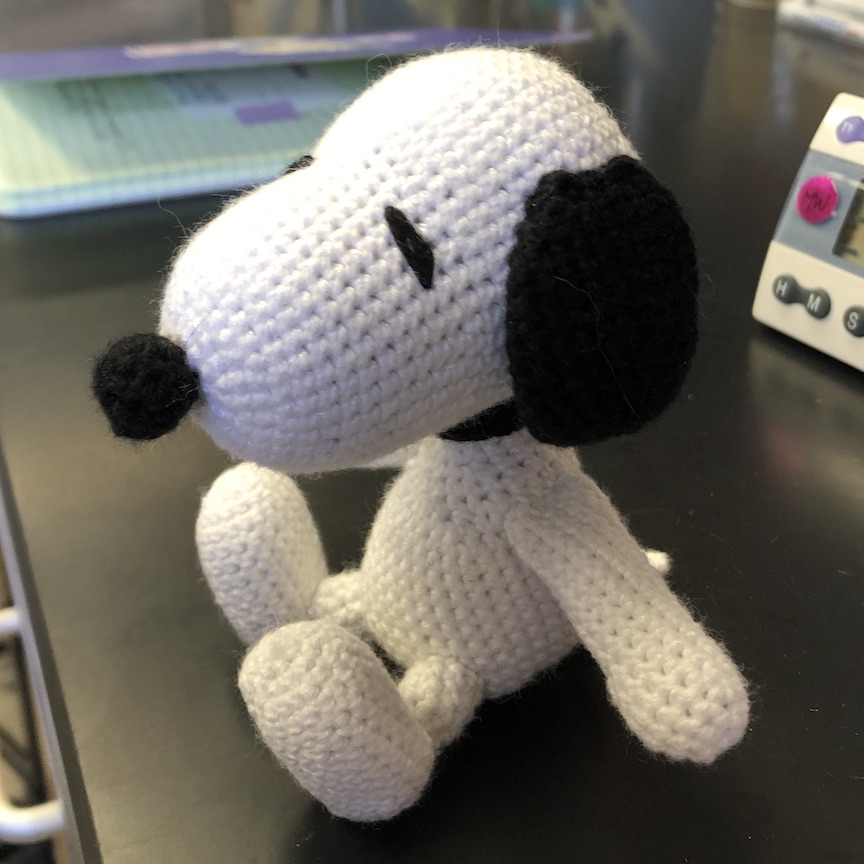 Crochet Snoopy sitting and looking off to the side