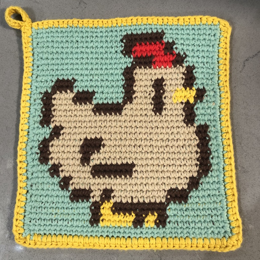 Crochet Stardew Valley chicken tapestry crochet hot pad with a blue background and yellow border