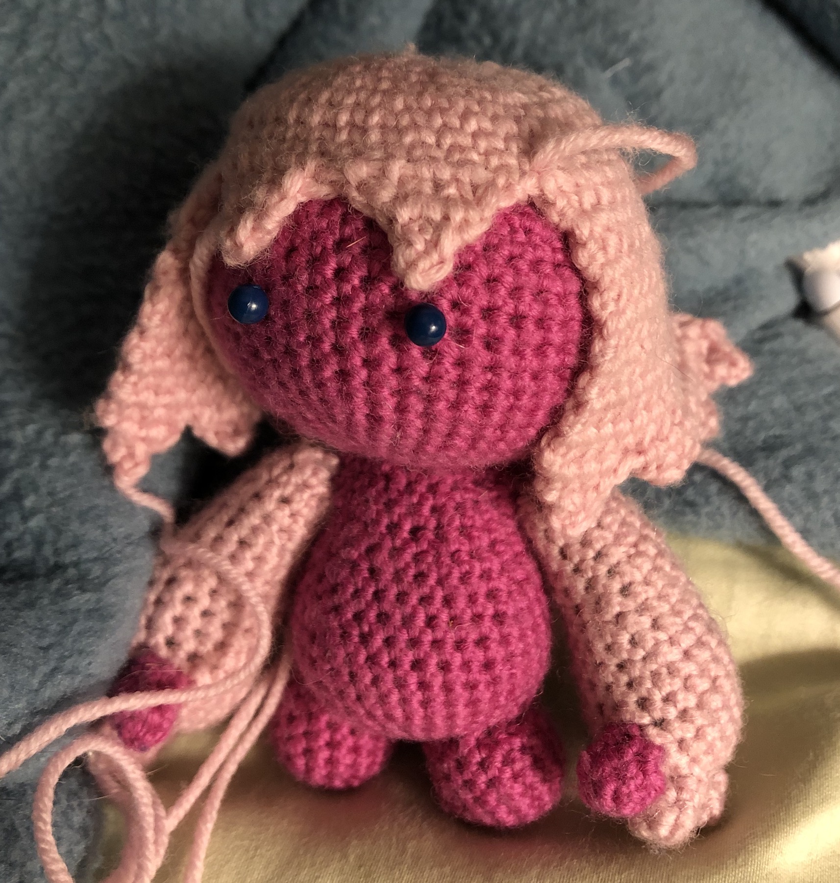 Crocheted head, body, limbs, now with unfinished hair which sits as triangle bangs and down to her shoulders
